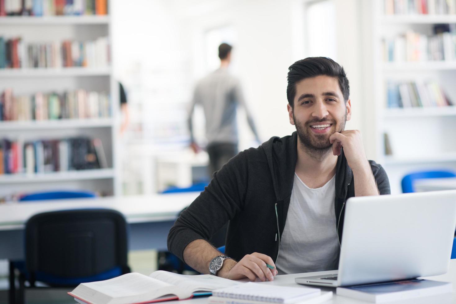 étudiant à la bibliothèque de l'école utilisant un ordinateur portable pour la recherche photo