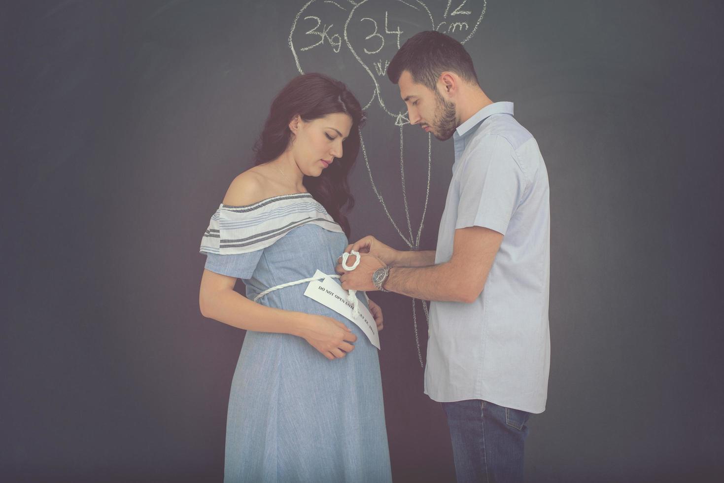 Couple enceinte dessinant leur imagination sur tableau noir photo