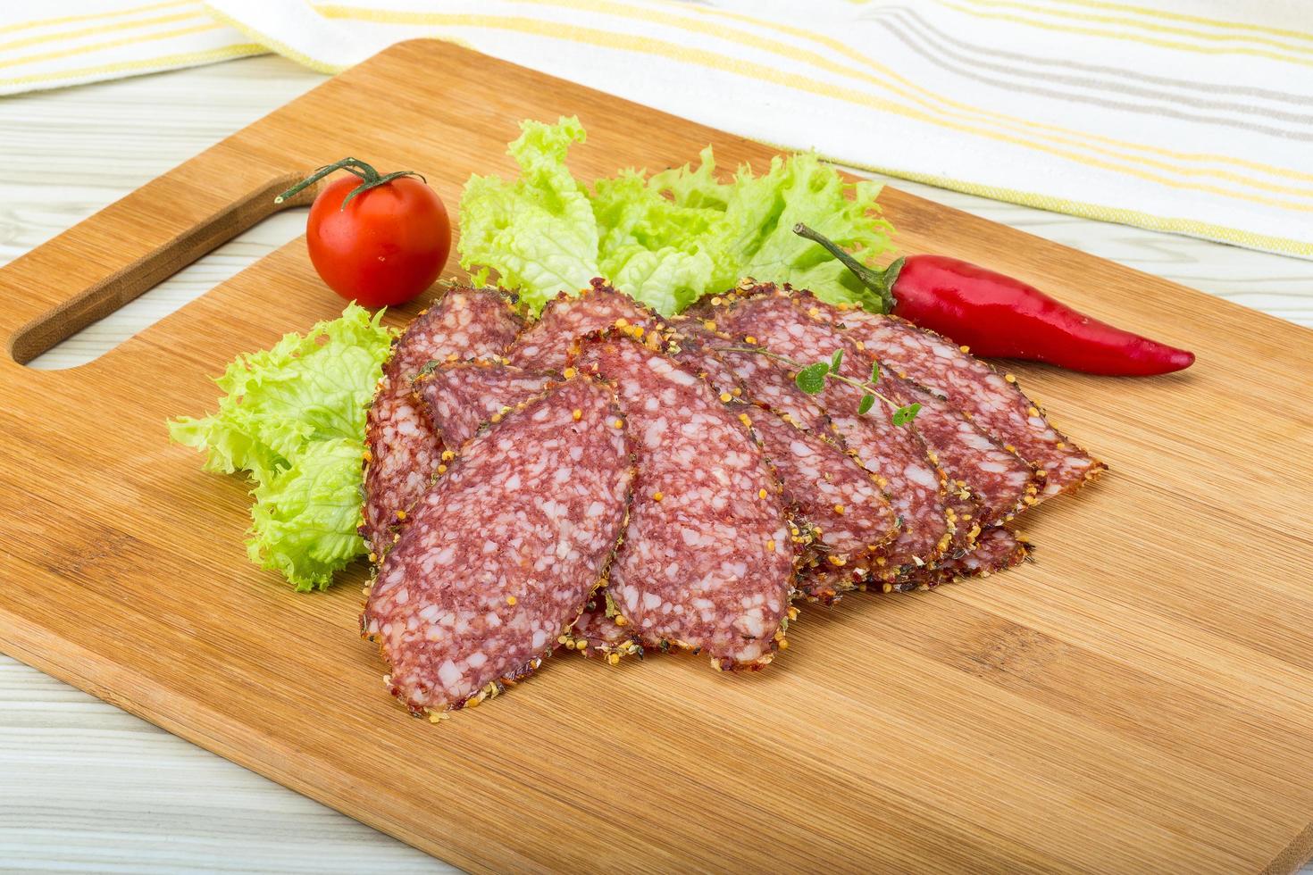 tranches de salami sur planche de bois et fond de bois photo