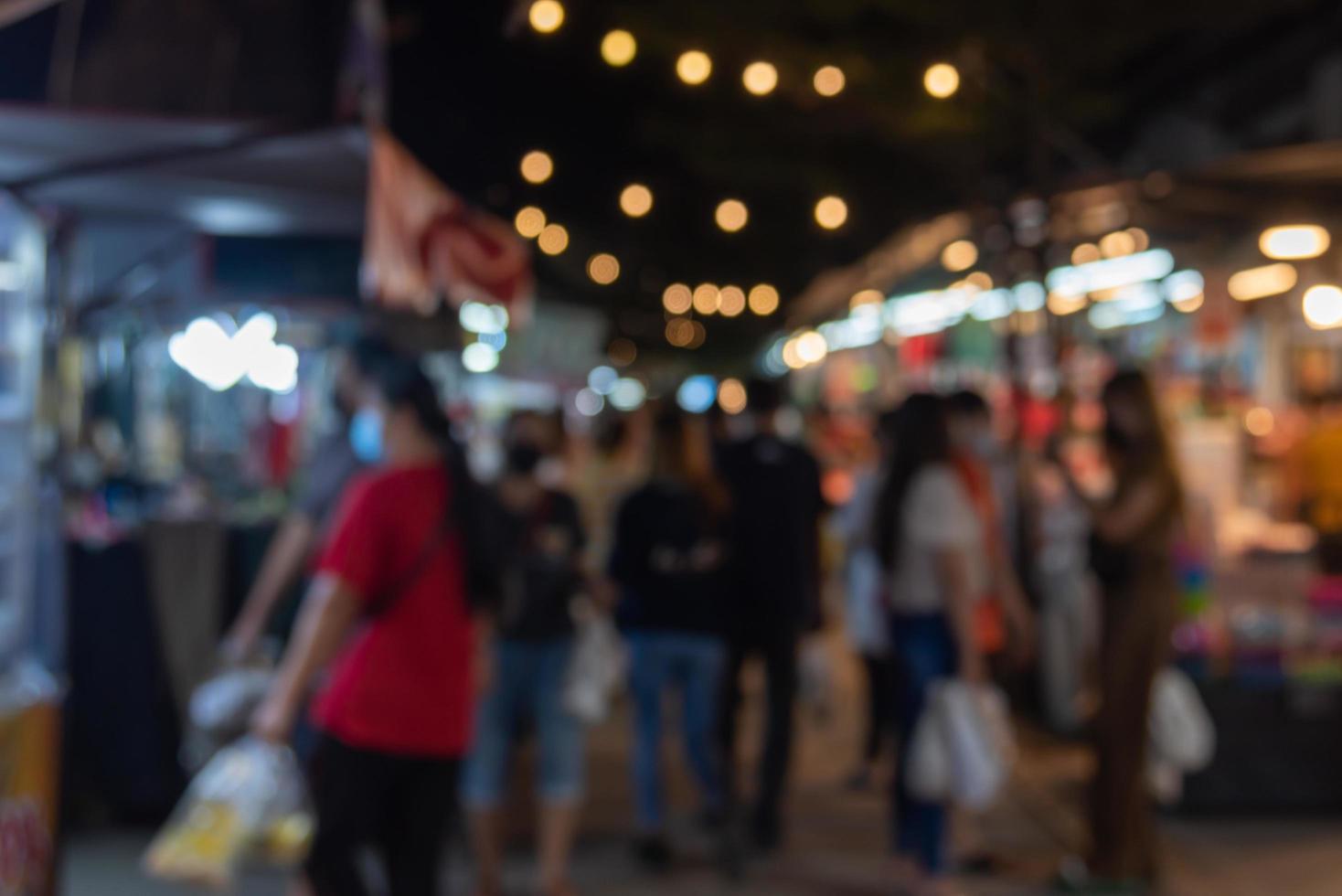 image floue des gens du festival du marché nocturne marchant sur la route avec un bokeh léger pour le fond. photo