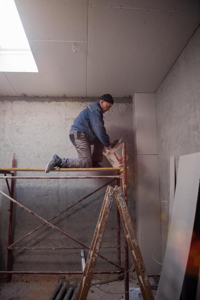 Travailleur de la construction plâtrage sur plafond de gypse photo