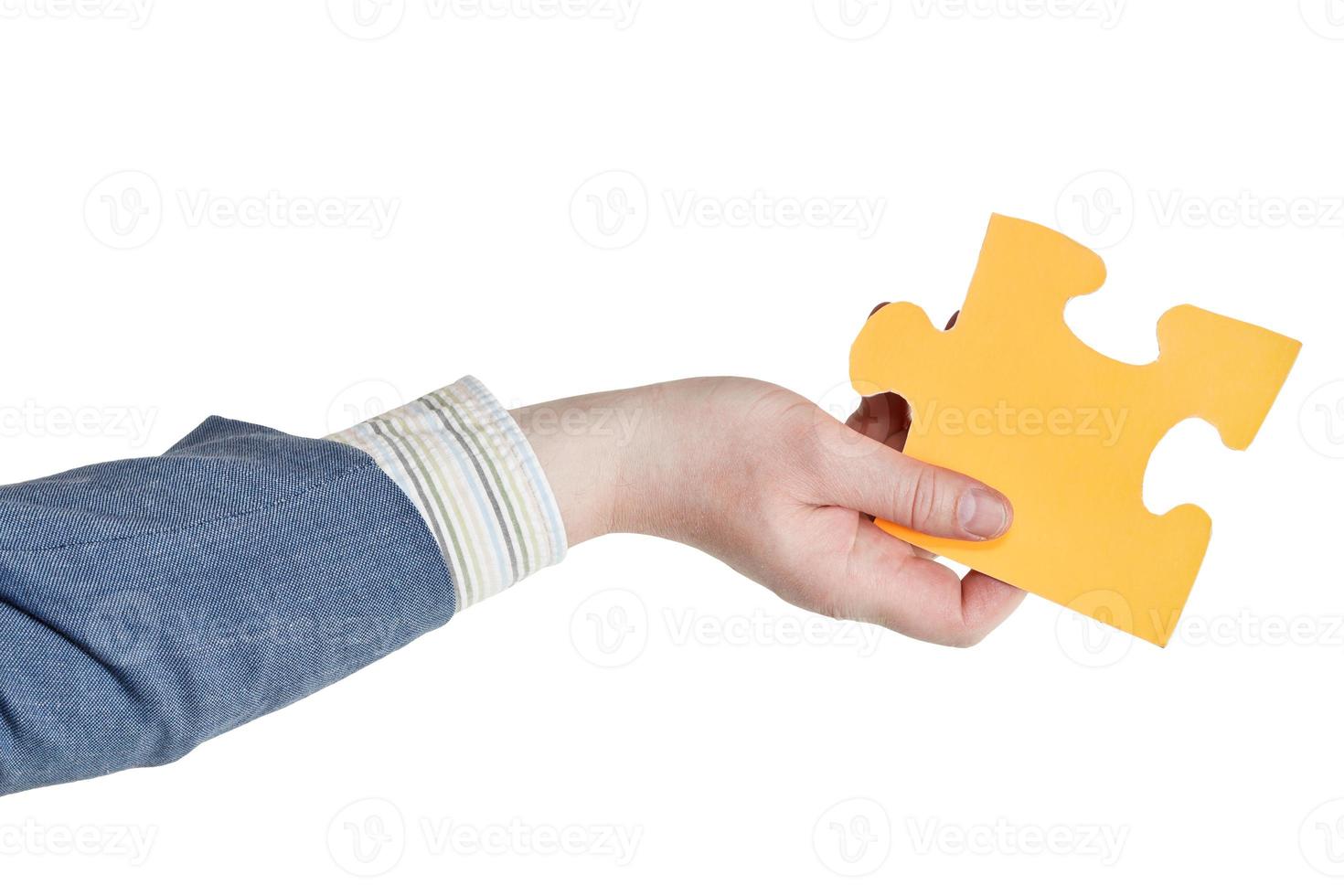 main masculine tenant une grande pièce de puzzle en papier jaune photo