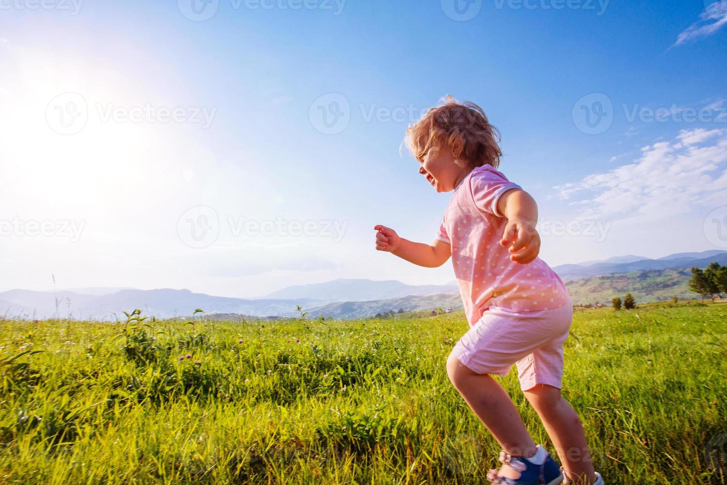 petite fille en bas âge courant dans un beau champ photo