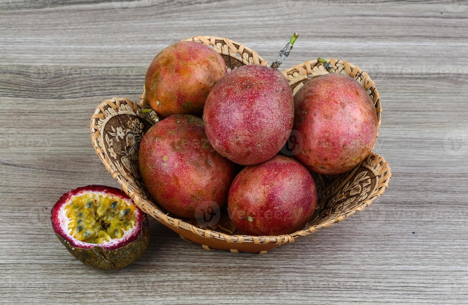 fruits tropicaux frais - maracuja dans un panier sur fond de bois photo