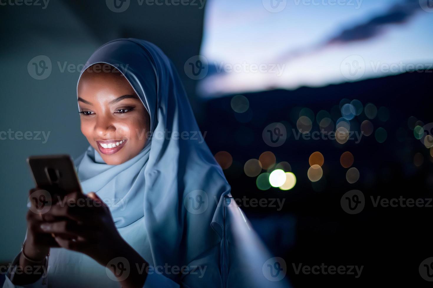 jeune femme musulmane dans la rue la nuit à l'aide de téléphone photo