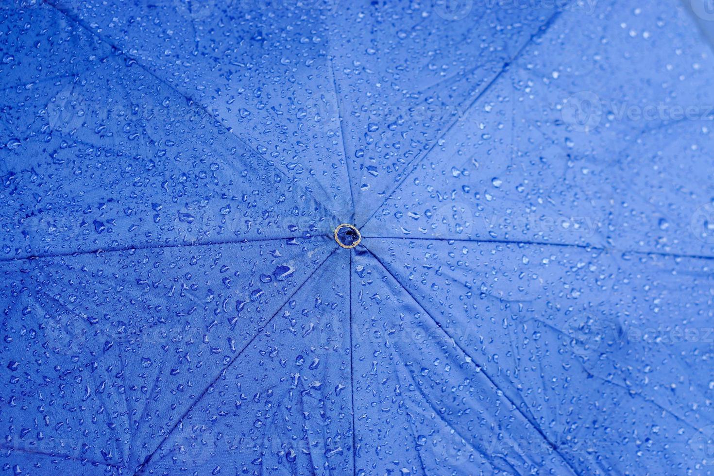 fond de vue de dessus et texture des gouttes de pluie sur le parapluie bleu. photo