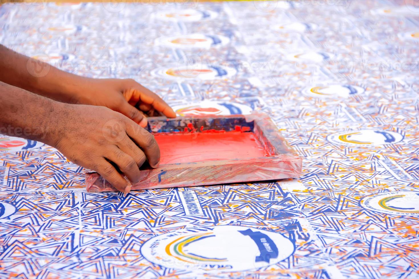 main un artiste pressant une raclette sur une boîte de sérigraphie pour imprimer sur du tissu. photo