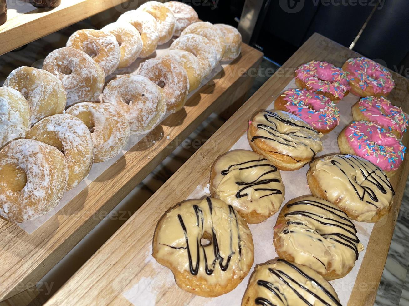 lignes de délicieux beignets frais dans une boulangerie, de délicieux beignets multiples, des beignets à mise au point sélective photo