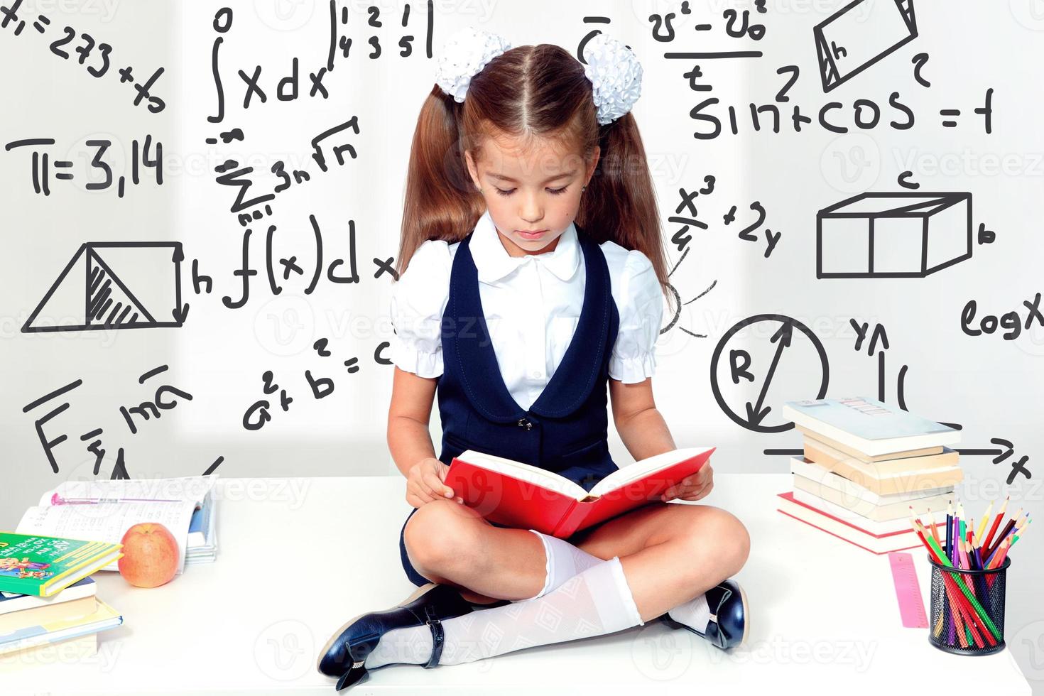 jeune fille mignonne assise à la table et lisant un livre photo