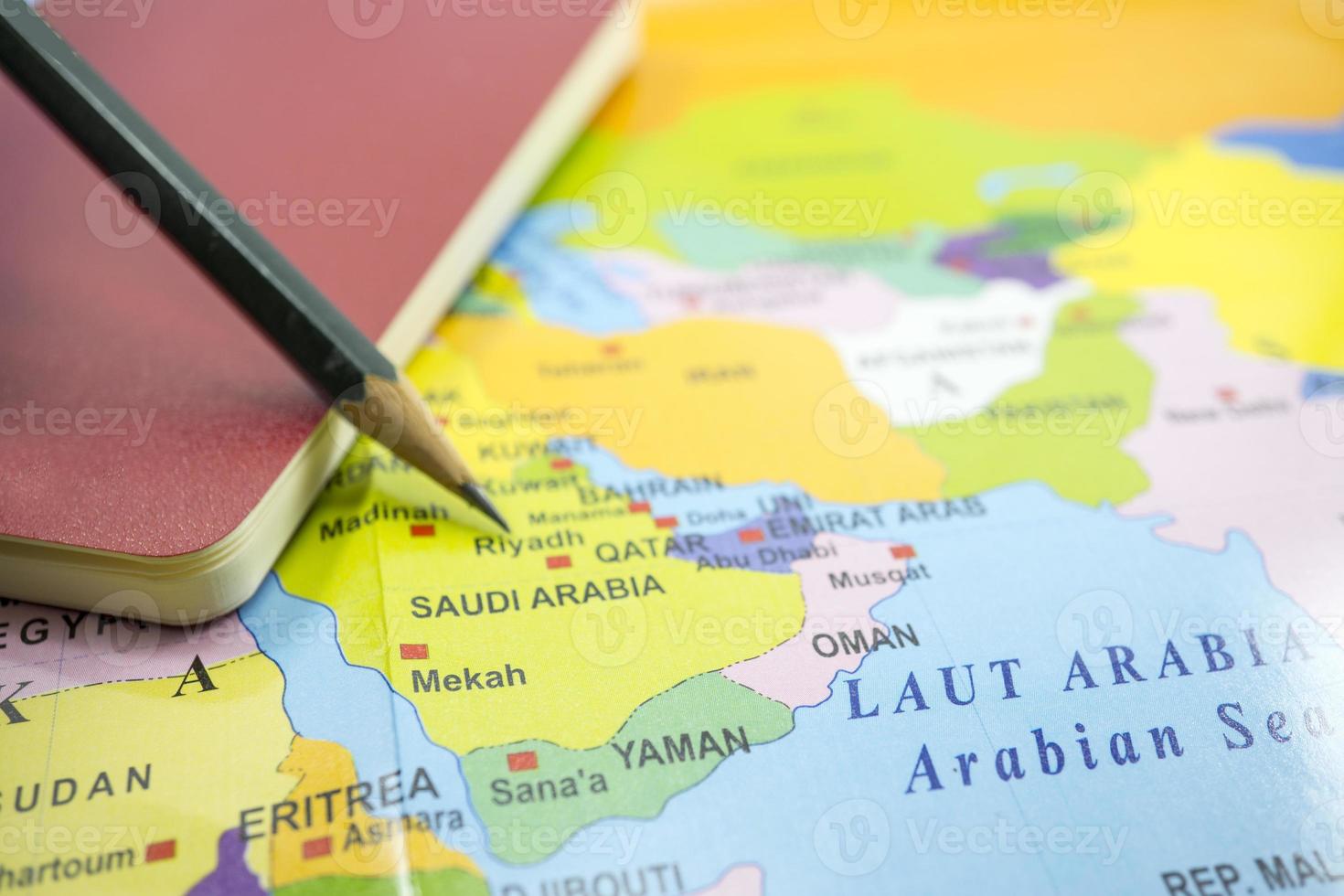 mise au point sélectionnée l'arabie saoudite sur une carte du monde avec un livre et un crayon. photo