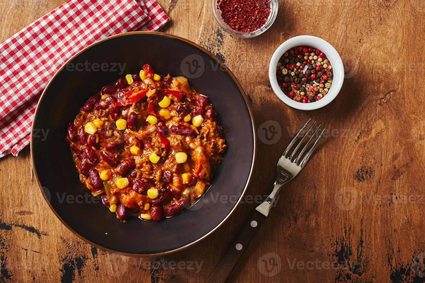 chili con carne avec boeuf haché, haricots et maïs dans un bol sombre sur fond bois. cuisine mexicaine et texane photo