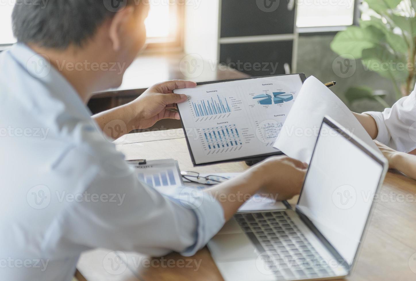 un homme d'affaires travaillant sur un ordinateur portable analyse des documents commerciaux avec des graphiques financiers. concept d'analyse de données d'entreprise. photo