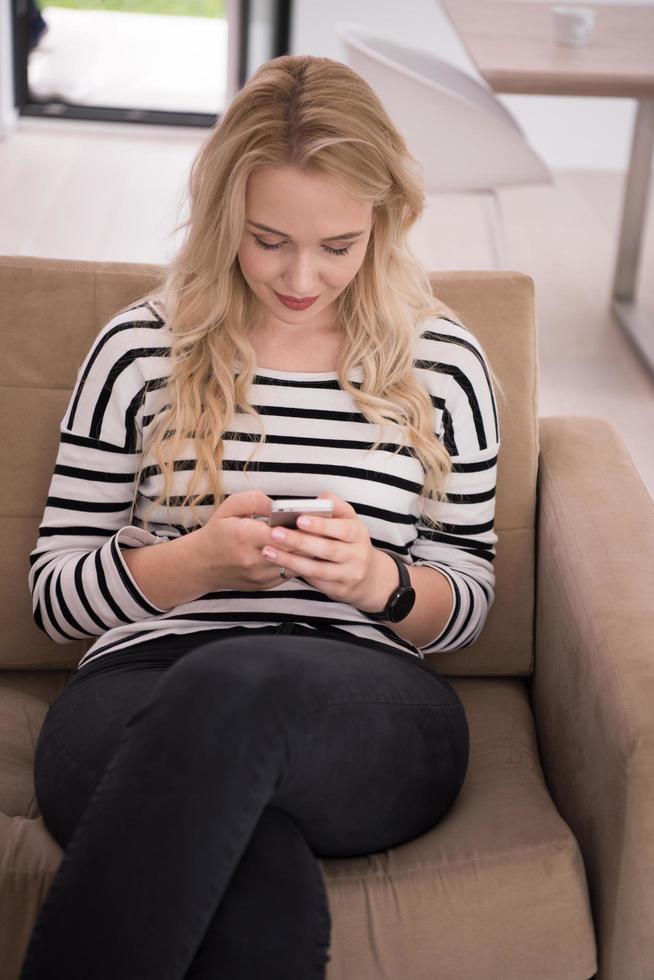 femme assise sur un canapé avec un téléphone portable photo