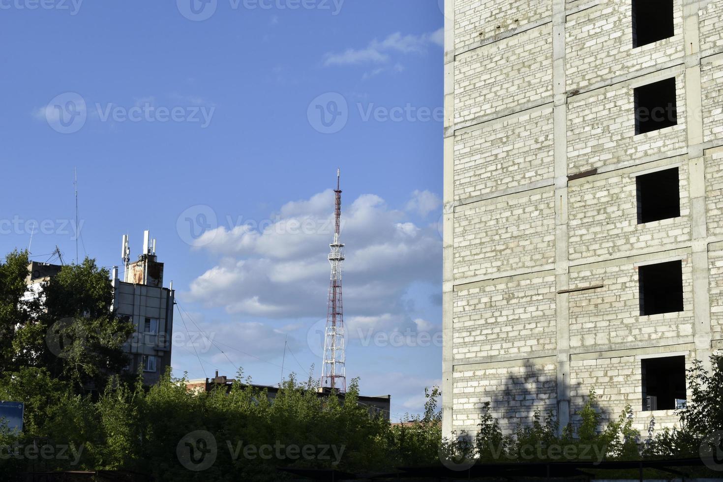 une antenne de télécommunications dans la ville et une grande roue avec une grande maison et un ciel bleu. photo