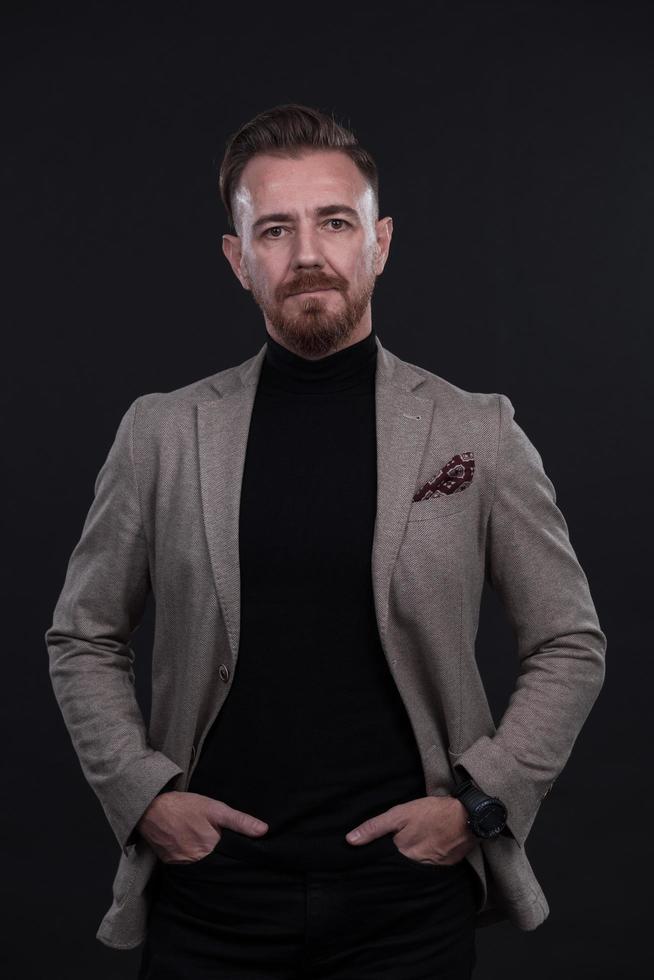 portrait d'un homme d'affaires élégant et élégant regardant la caméra dans un studio photo sur fond sombre avec une lumière dure