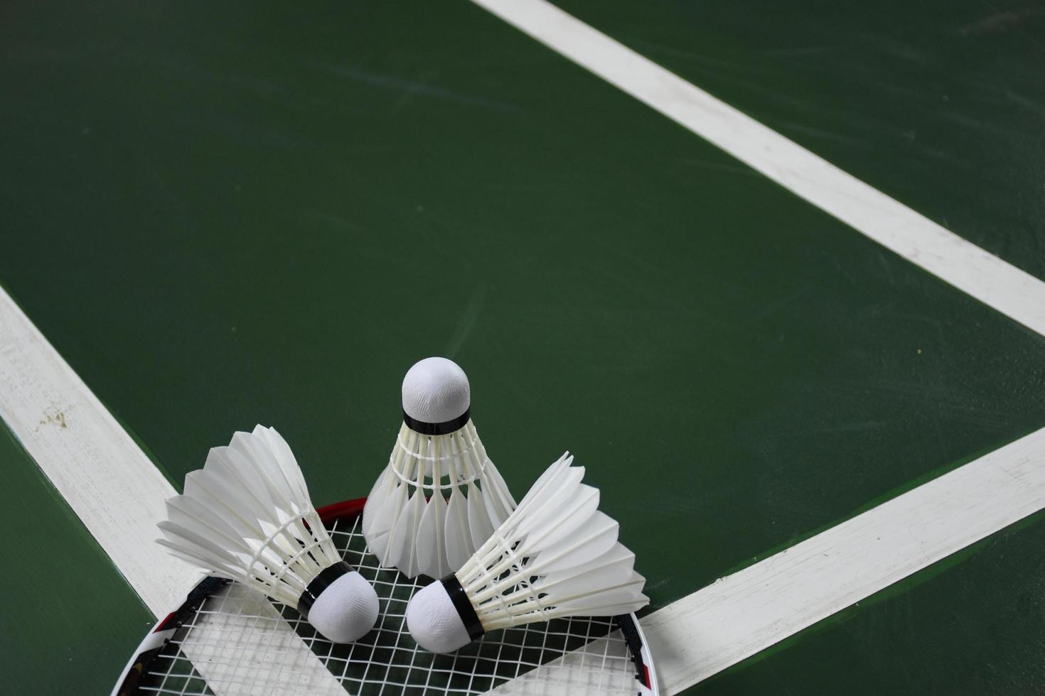 Volant et raquette de badminton blanc crème sur sol rouge dans un terrain de badminton intérieur, espace de copie, mise au point douce et sélective sur les volants. photo