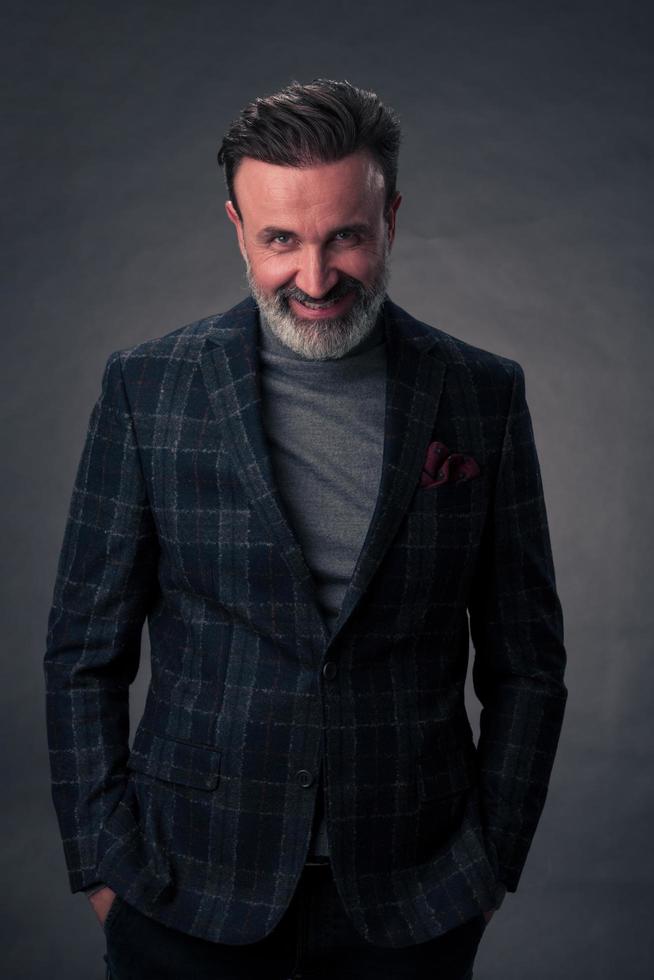 portrait d'un homme d'affaires senior élégant et élégant avec une barbe et des vêtements d'affaires décontractés en studio photo isolé sur fond sombre gesticulant avec les mains