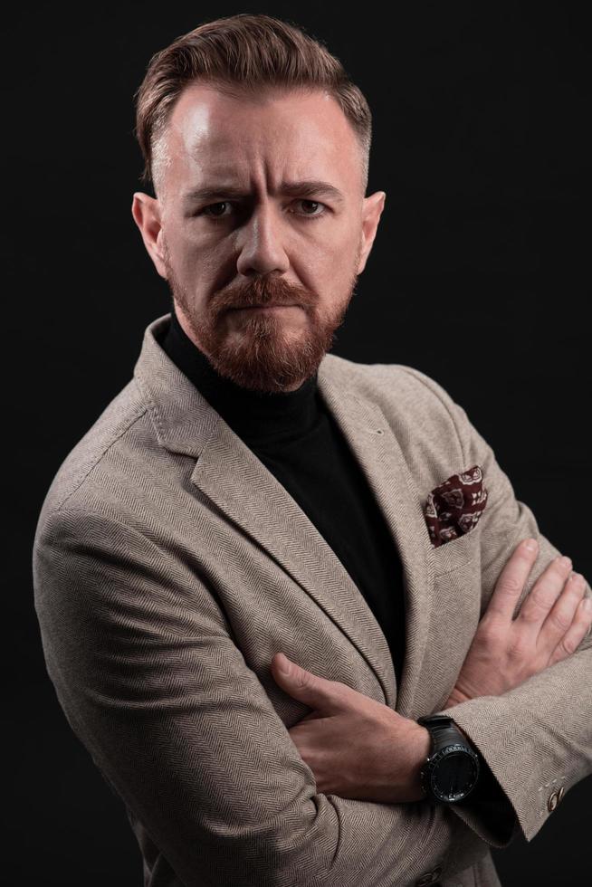 portrait d'un homme d'affaires senior élégant et élégant avec une barbe et des vêtements d'affaires décontractés en studio photo isolé sur fond sombre gesticulant avec les mains