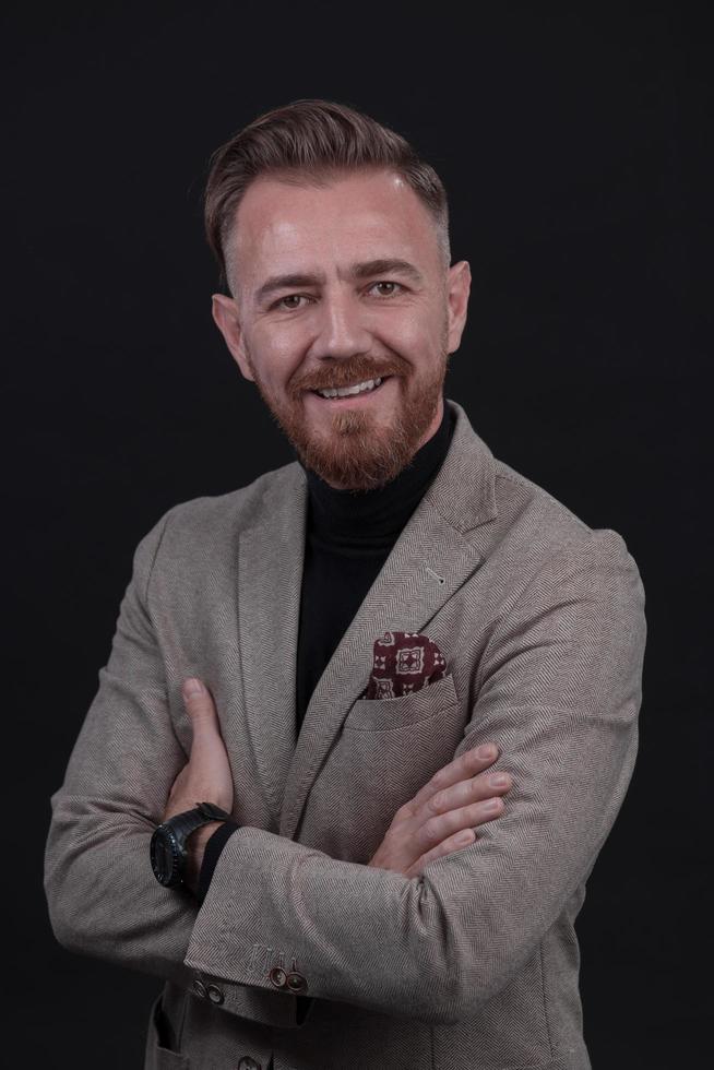 portrait d'un homme d'affaires senior élégant et élégant avec une barbe et des vêtements d'affaires décontractés en studio photo isolé sur fond sombre gesticulant avec les mains