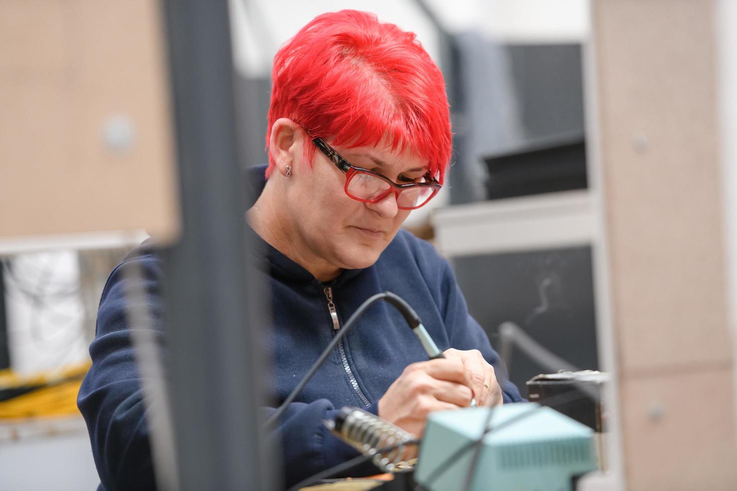 Travailleur industriel femme souder des câbles d'équipements de fabrication dans une usine photo