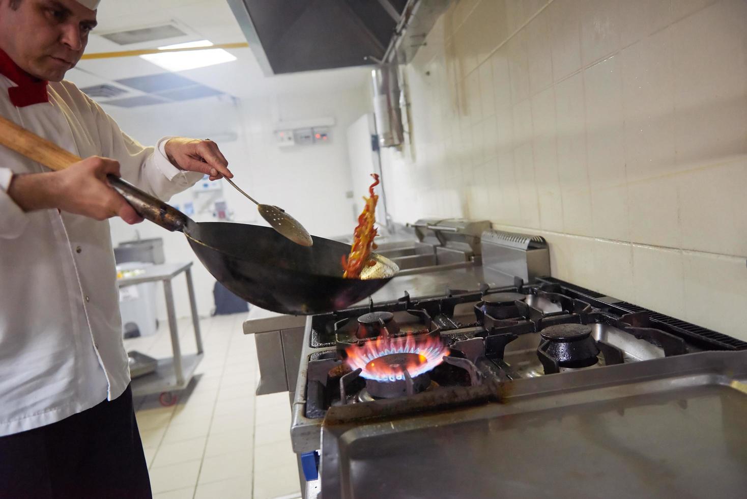 le chef de la cuisine de l'hôtel prépare la nourriture avec le feu photo