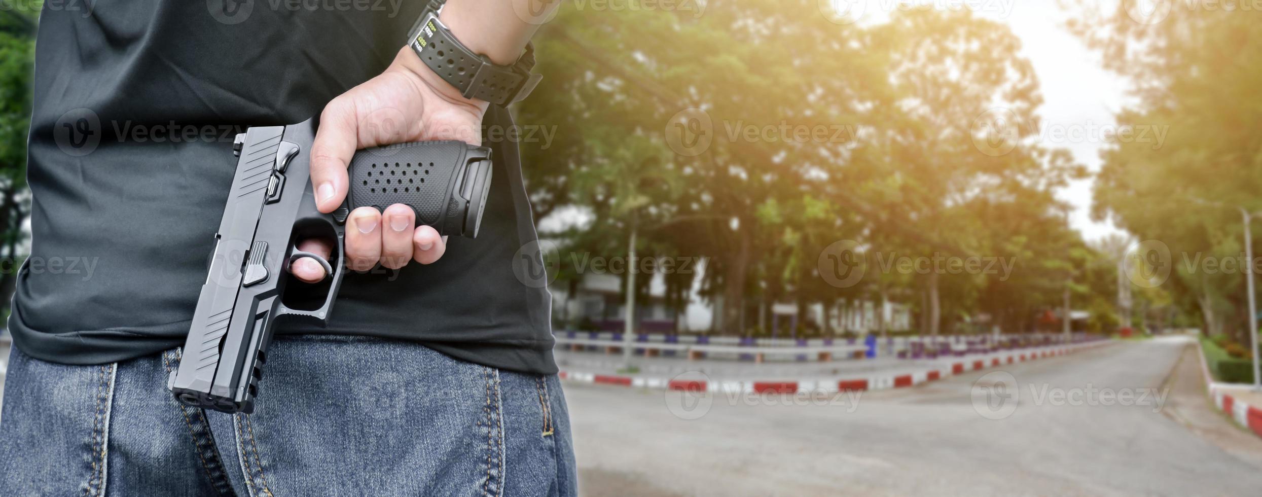 Pistolet automatique de 9 mm tenant dans la main droite du tireur, concept de sécurité, vol, gangster, garde du corps dans le monde entier. mise au point sélective sur le pistolet. photo