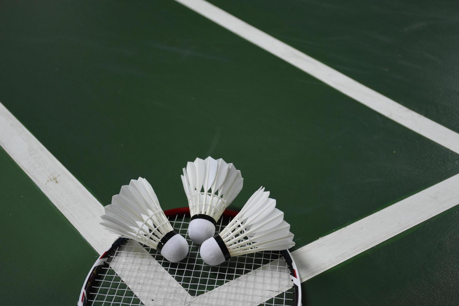 Volant et raquette de badminton blanc crème sur sol rouge dans un terrain de badminton intérieur, espace de copie, mise au point douce et sélective sur les volants. photo