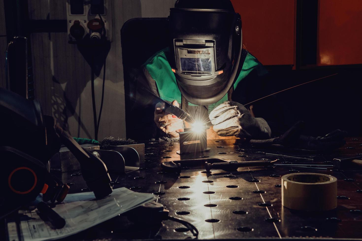 une femme employée dans une usine moderne pour la production et la transformation de métaux dans un uniforme de travail soudant des matériaux métalliques photo