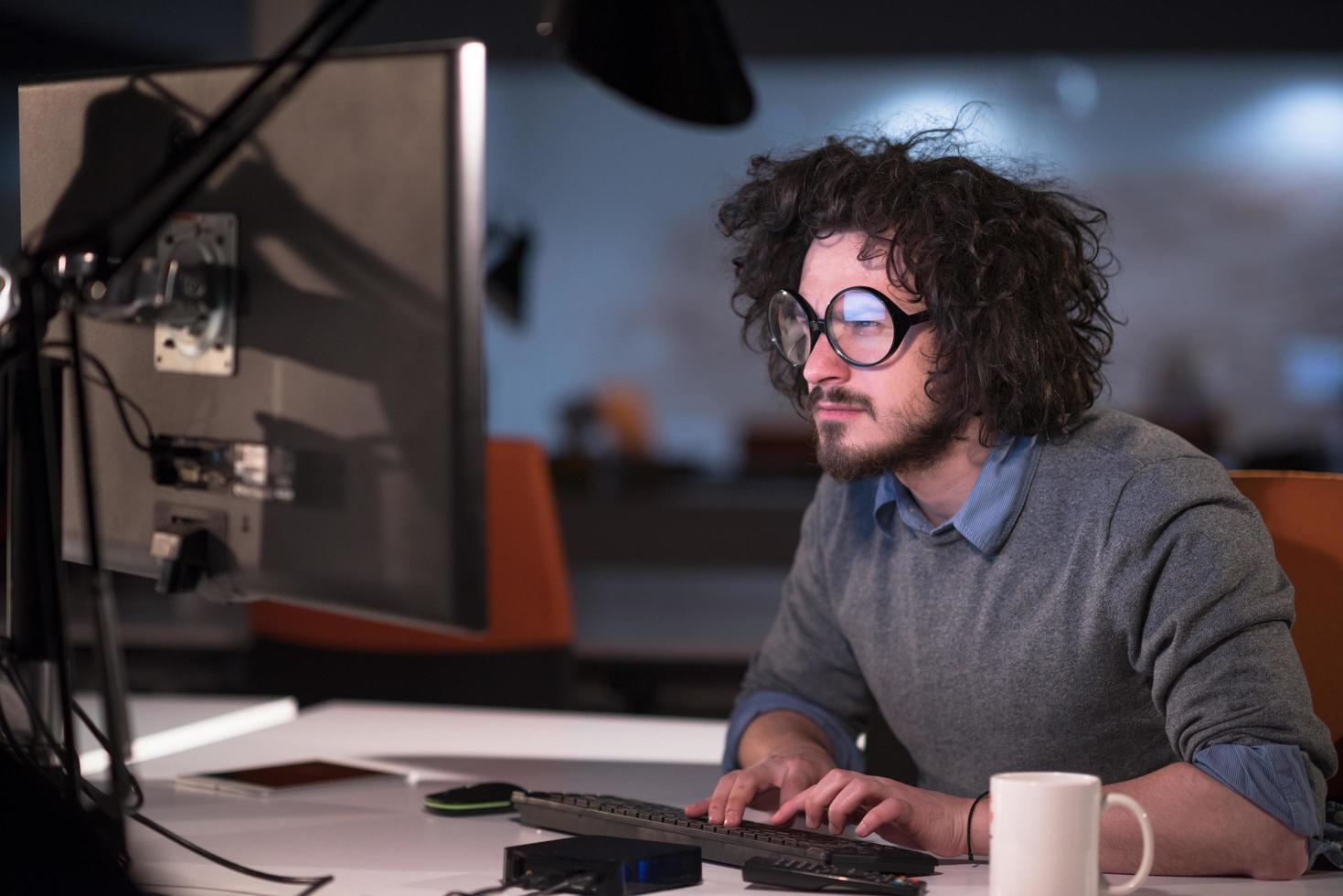 homme travaillant sur ordinateur dans un bureau de démarrage sombre photo