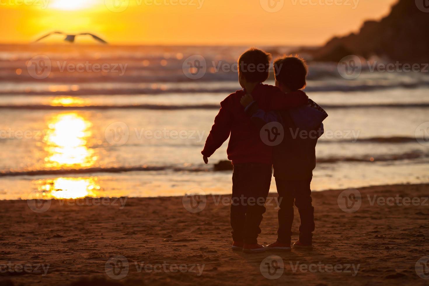belle photo de deux garçons sur la plage au coucher du soleil