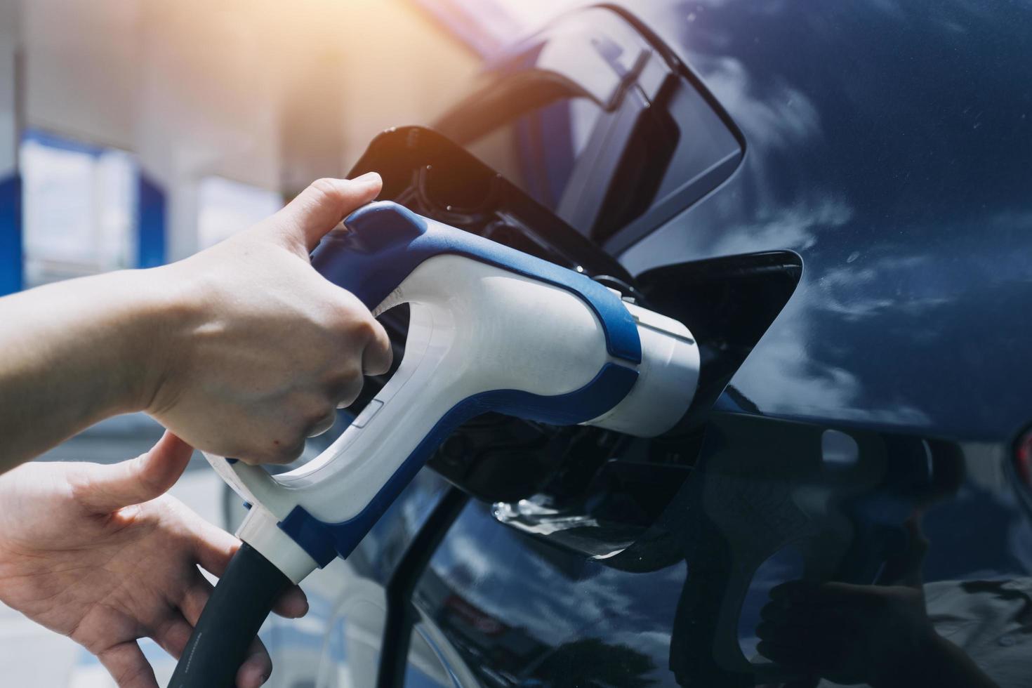 brancher à la main un chargeur dans une prise de voiture électrique.voiture électrique ou ev se recharge à la station photo