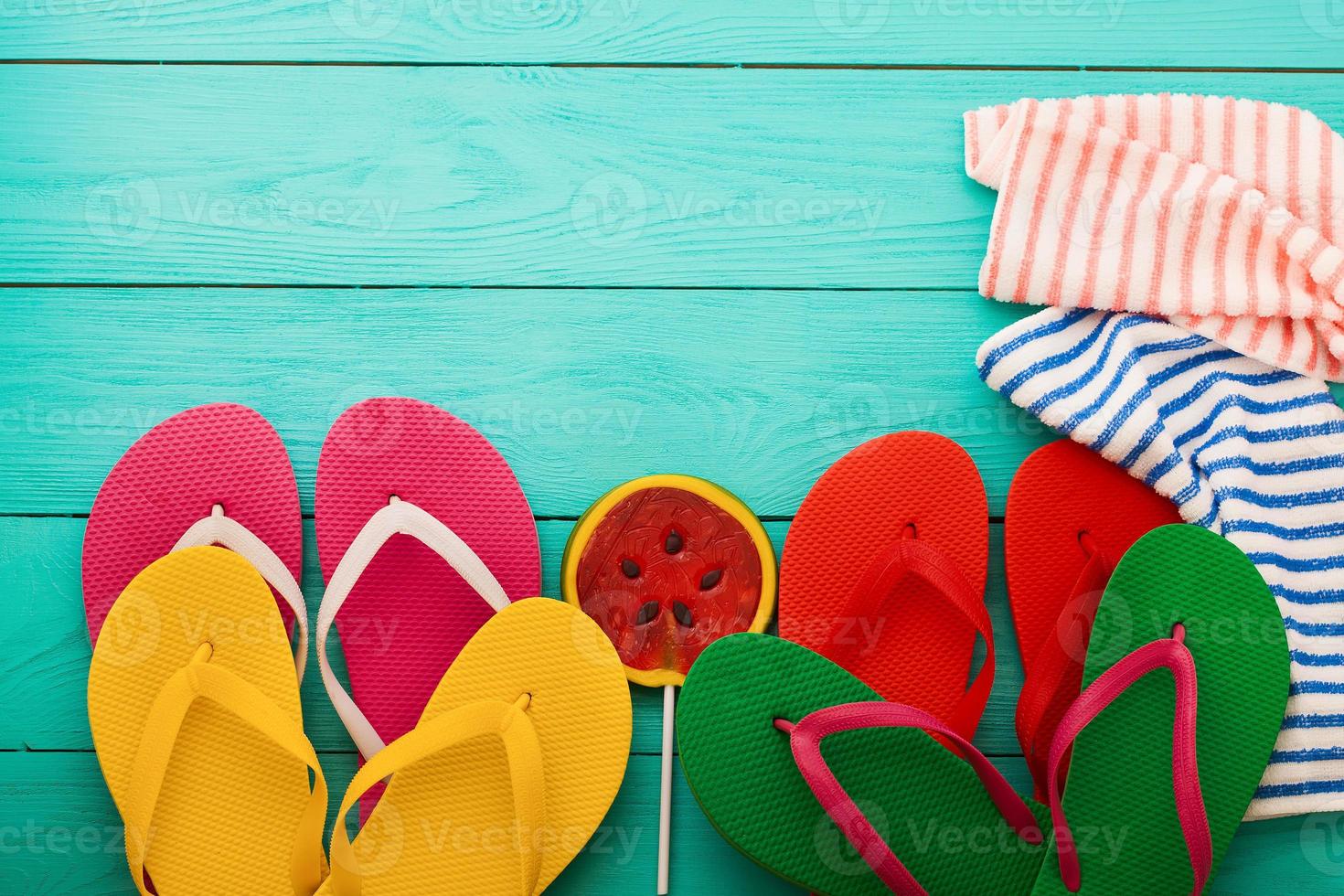 tongs, bonbons à la pastèque et serviette. accessoires de plage d'été et espace de copie sur fond en bois bleu. vue de dessus photo