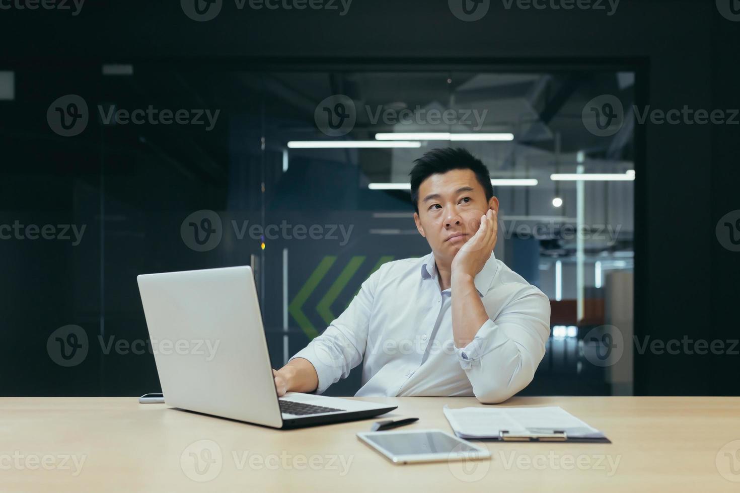 homme d'affaires asiatique pensif travaillant dans un bureau moderne, homme pensant photo
