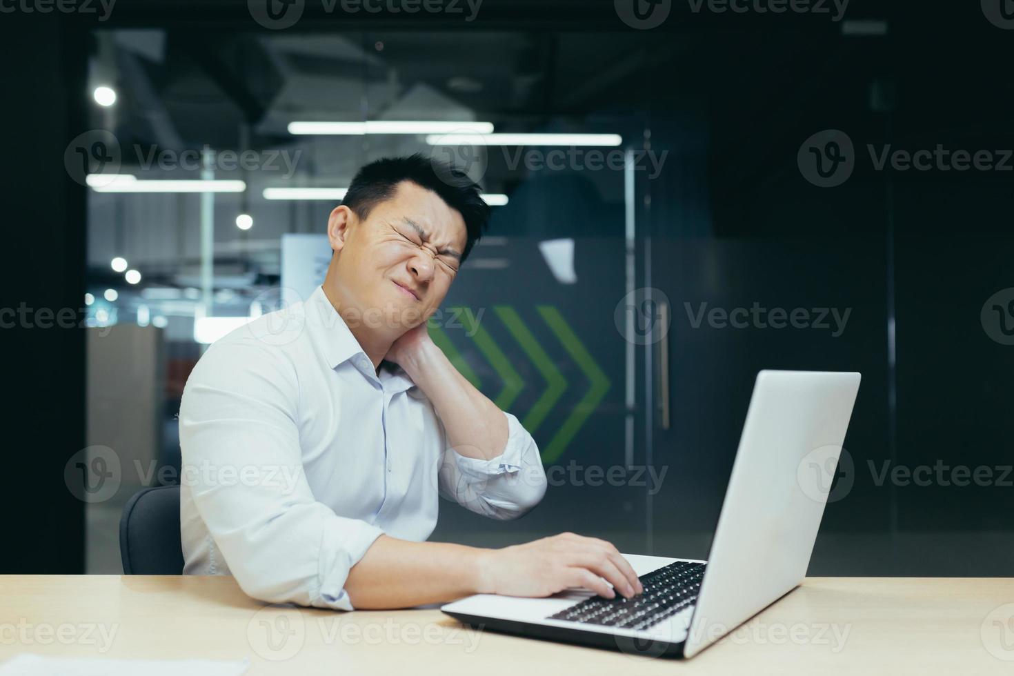 Travailleur asiatique fatigué au bureau, ayant de graves douleurs au cou photo