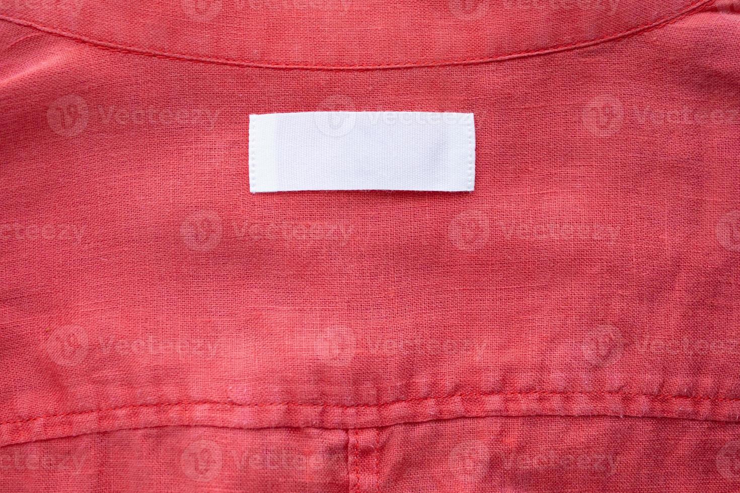 Étiquette d'étiquette de vêtements blanc vierge sur fond de texture de tissu de chemise en lin rouge photo