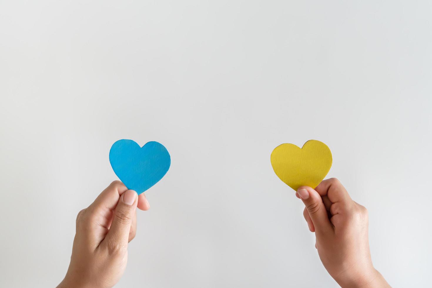 sauver l'ukraine arrêter la guerre. mains tenant un coeur en papier dans la couleur du drapeau national de l'ukraine. photo