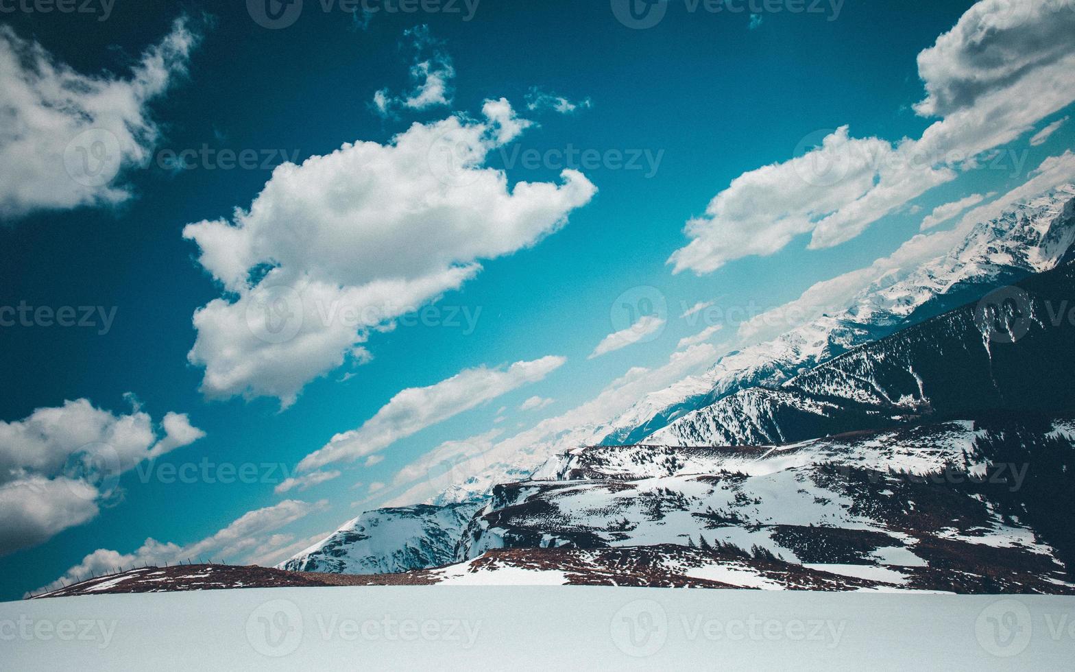 une photo angulaire de montagnes enneigées sous des nuages duveteux