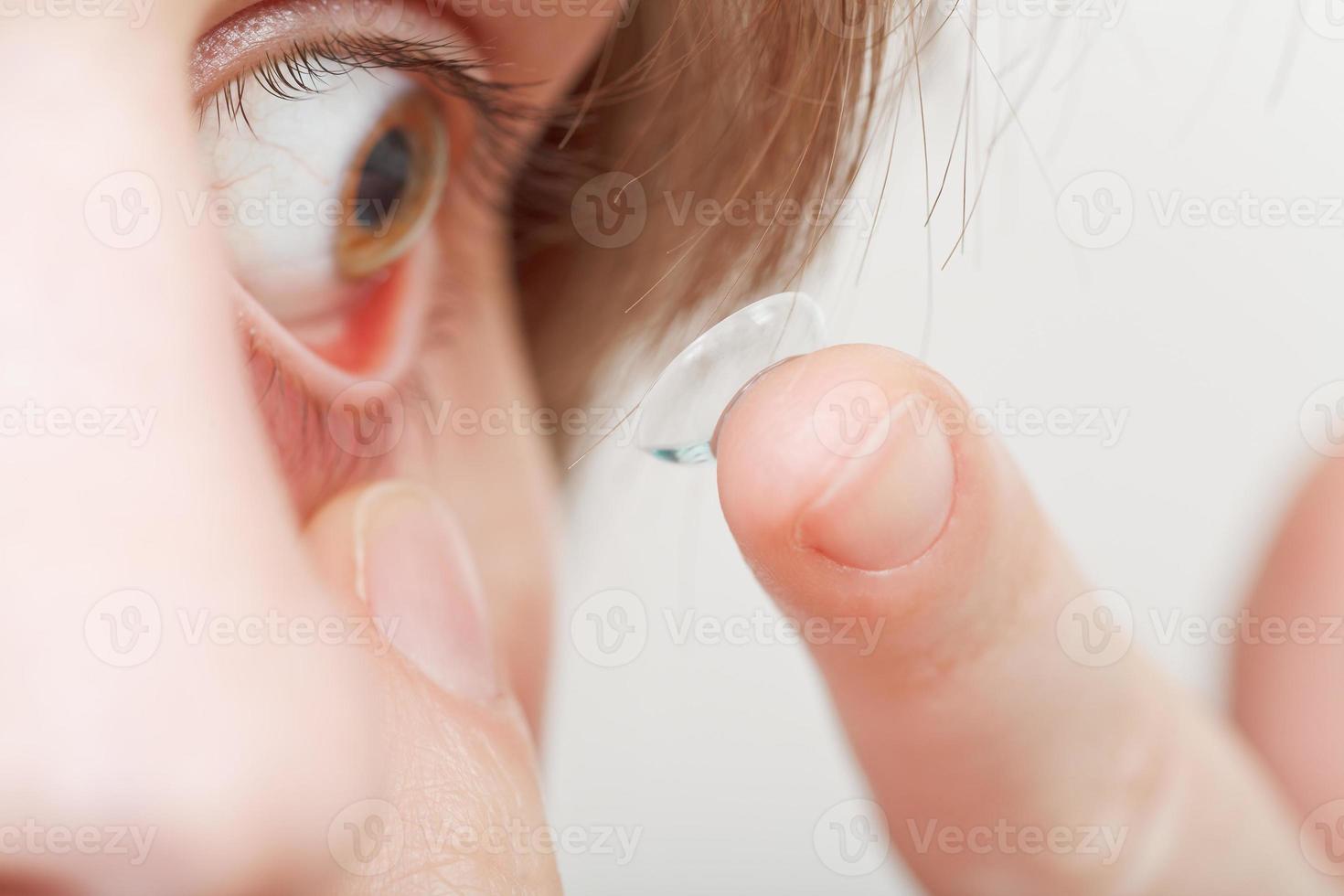 jeune femme insérant une lentille de contact photo