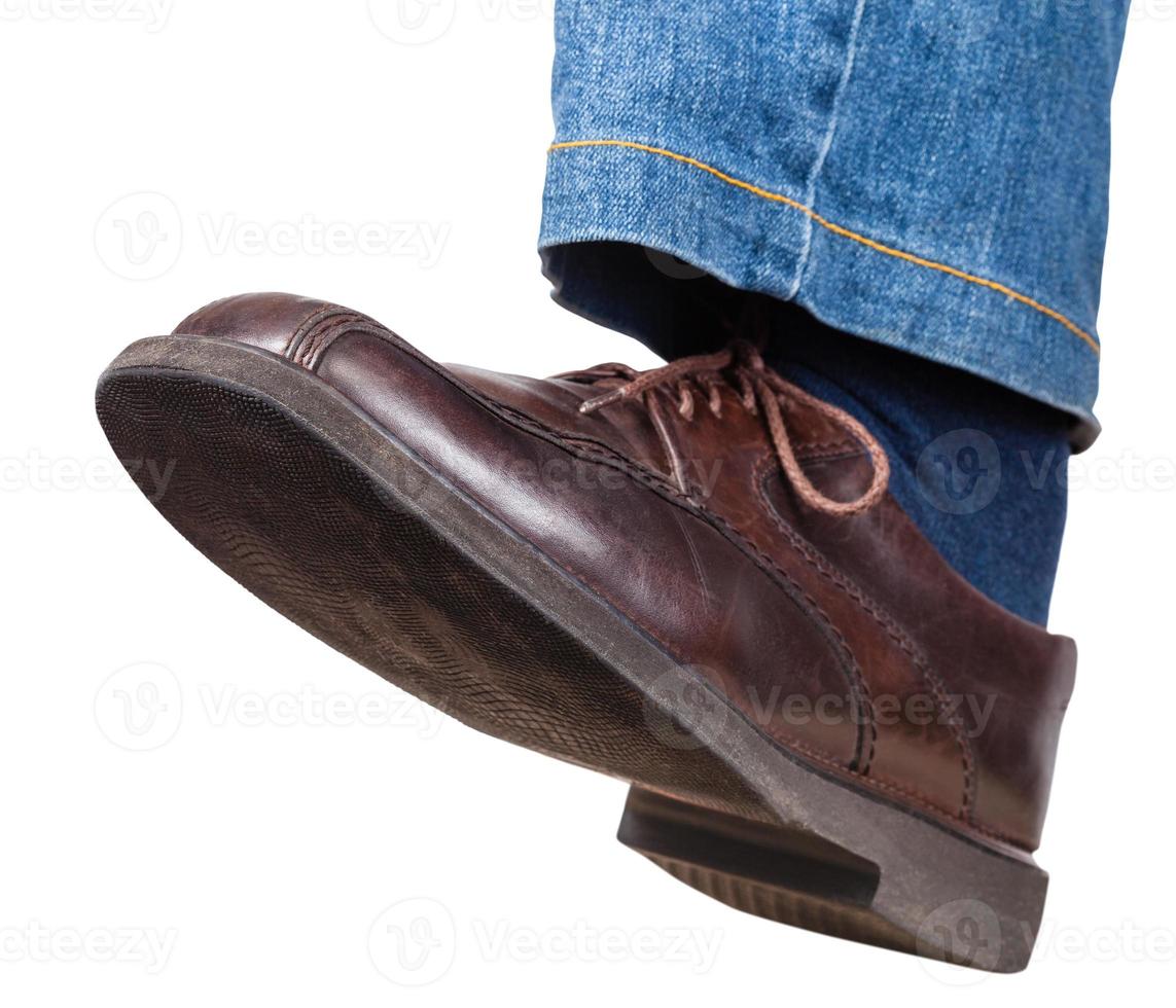étape de la jambe gauche masculine en jeans et chaussures marron photo