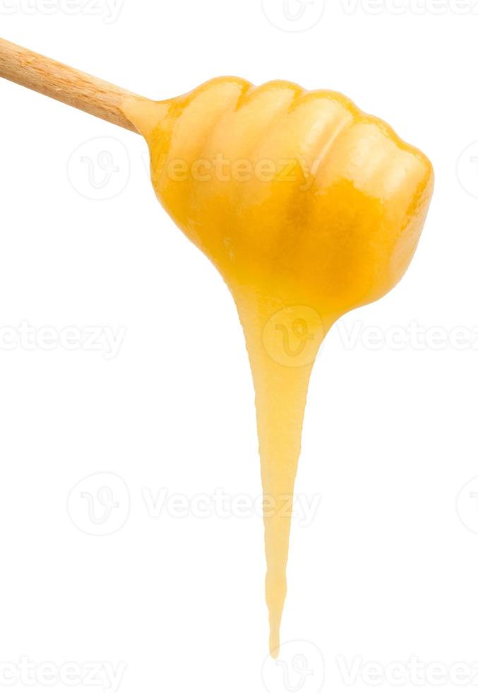 le miel jaune coule de la cuillère en bois se bouchent photo
