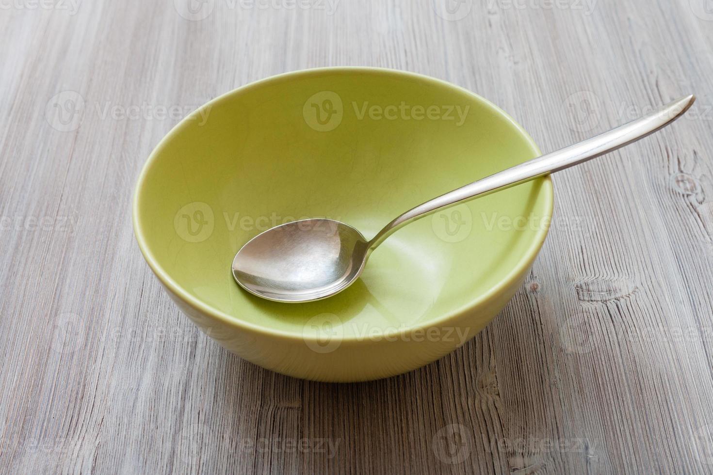 bol vert avec cuillère en acier sur table marron gris photo