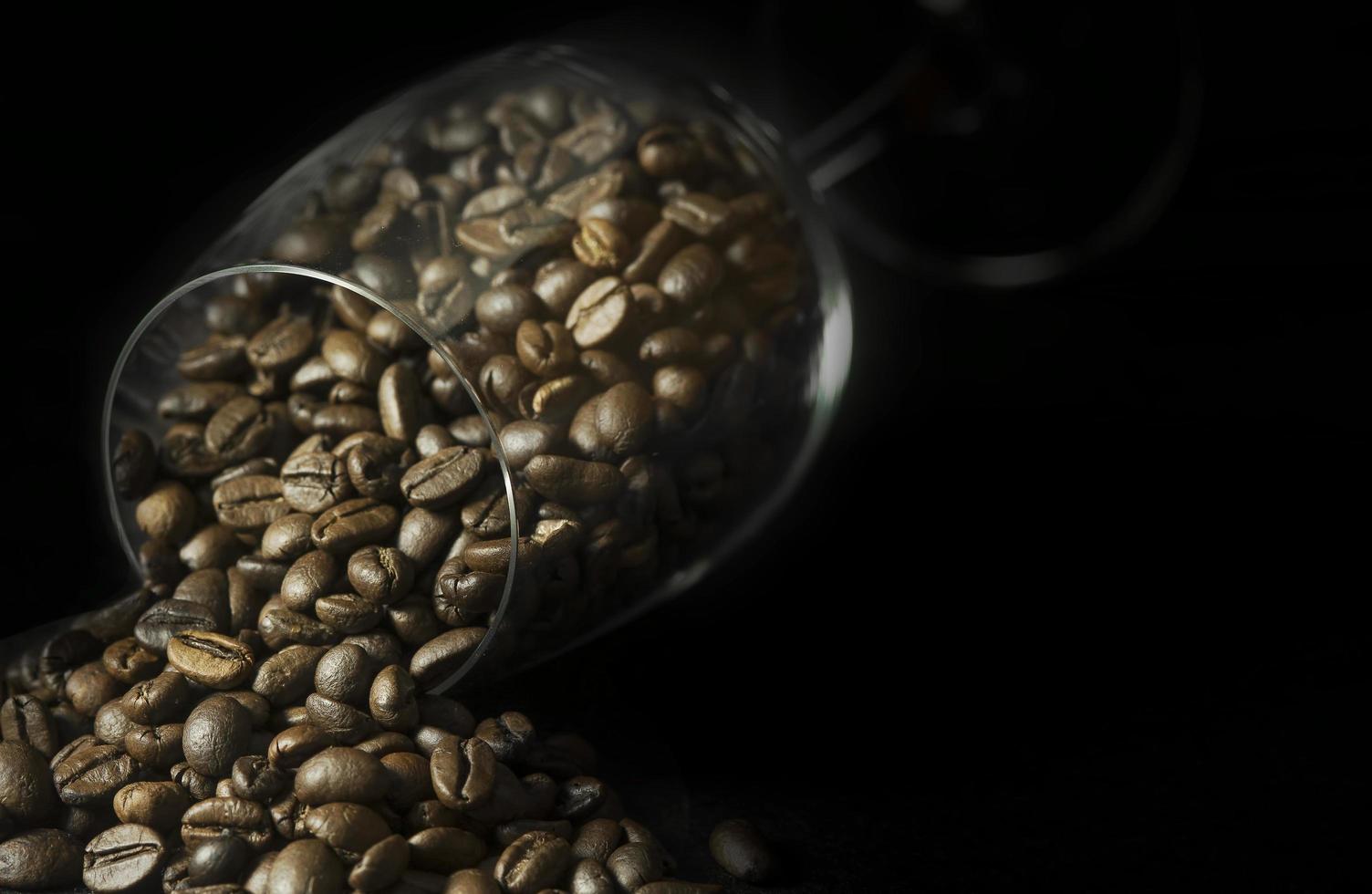 grains de café en verre à vin sur fond noir photo