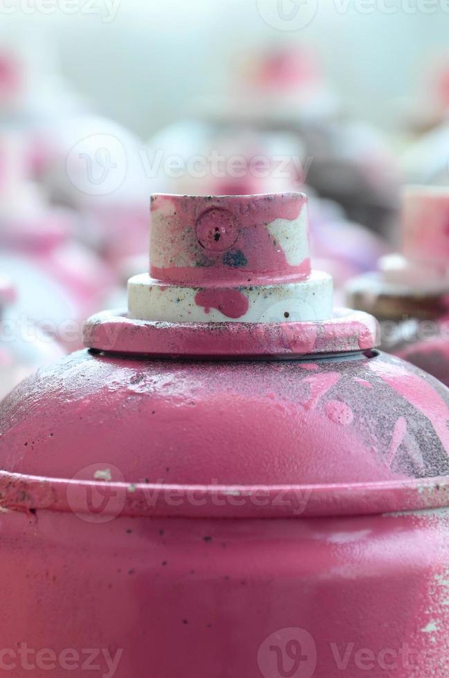 beaucoup de bombes aérosols sales et usagées de peinture rose vif. photographie macro avec une faible profondeur de champ. mise au point sélective sur la buse de pulvérisation photo