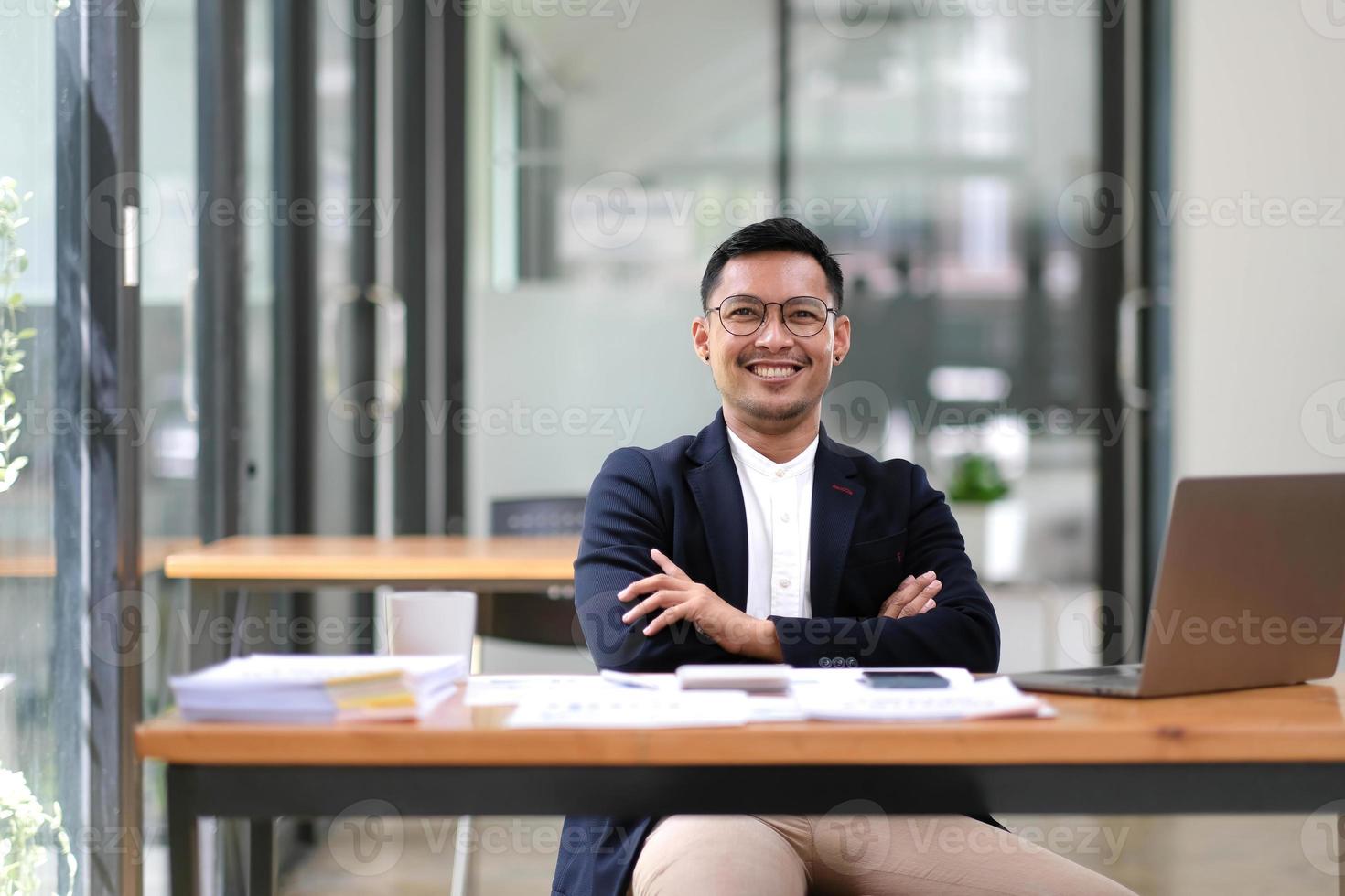 portrait d'un bel homme d'affaires exécutif réussi, intelligent, regardant la caméra et souriant, heureux dans un lieu de travail de bureau moderne. photo