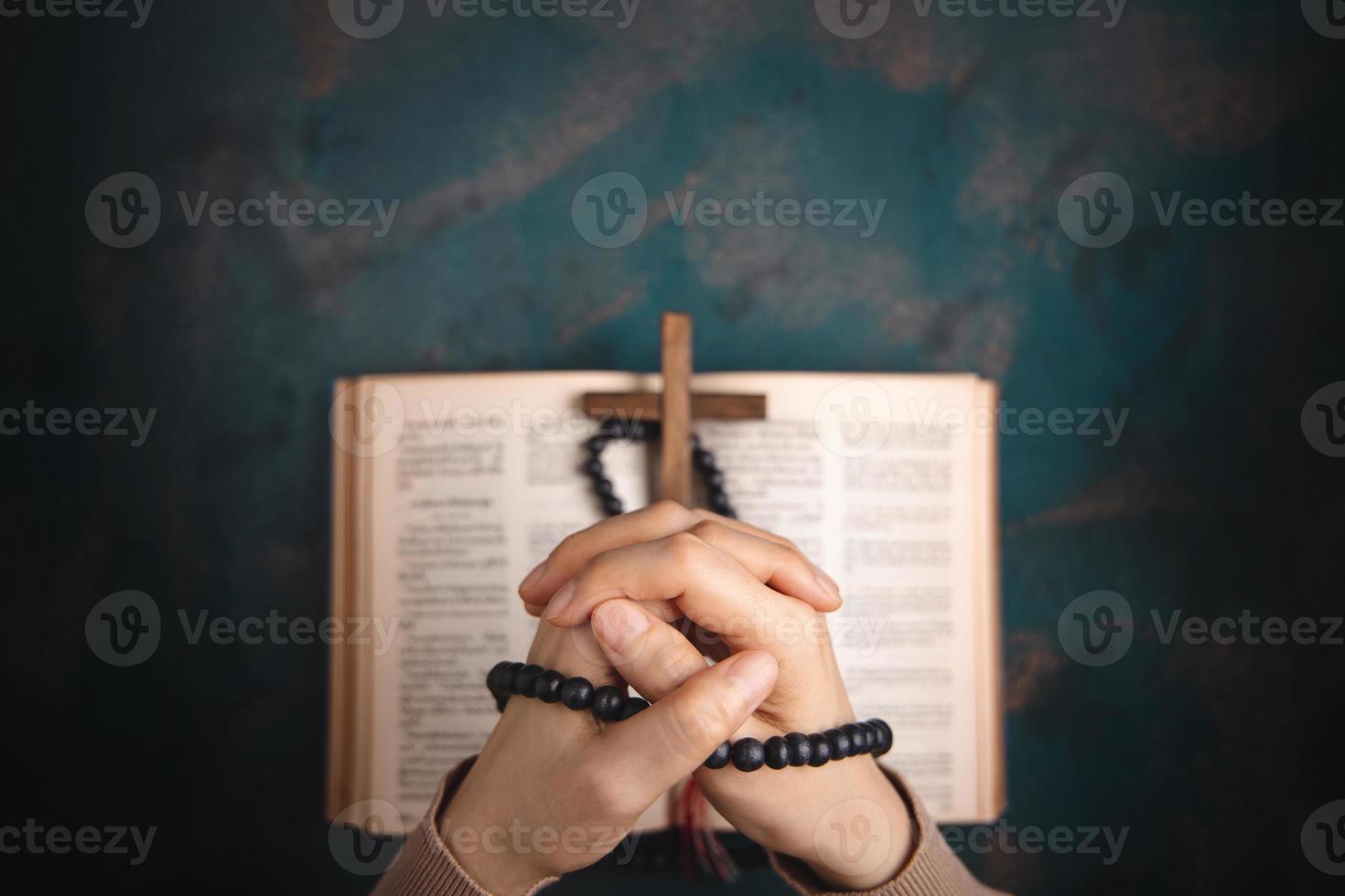 concept de spiritualité, de religion et d'espoir. personne priant par la sainte bible et croix sur le bureau. symbole d'humilité, de supplication, de croyance et de foi pour le peuple chrétien. vue de dessus photo