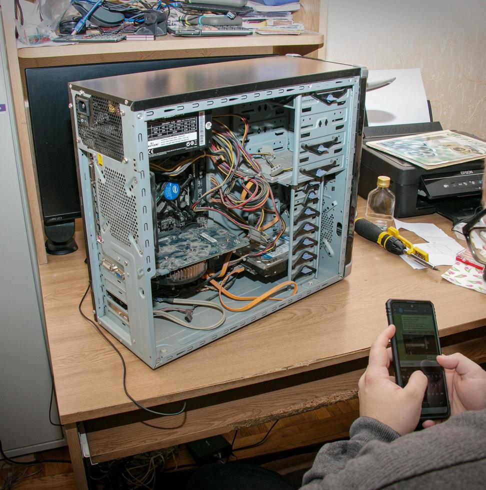 démontage d'un vieil ordinateur poussiéreux. le programmeur identifie les parties de l'unité centrale à l'aide d'Internet. photo