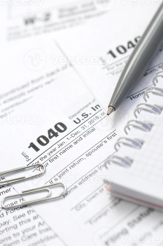 le stylo et le cahier se trouvent sur le formulaire fiscal 1040 déclaration de revenus des particuliers américains. le temps de payer les impôts photo