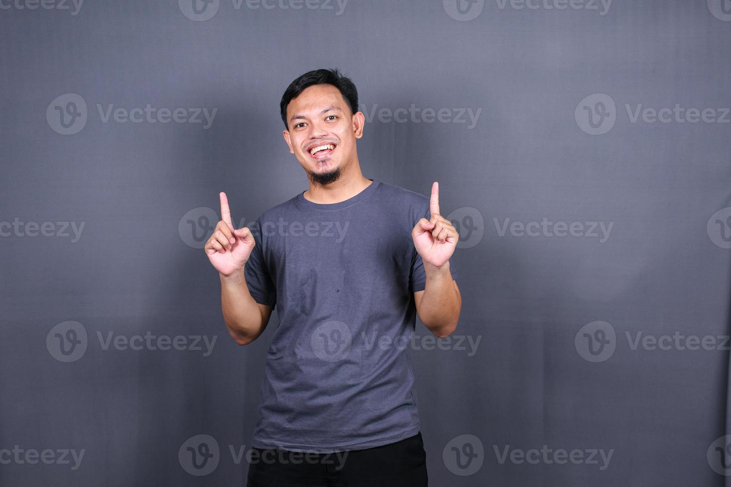 jeune homme asiatique souriant et séduisant en t-shirt posant isolé sur fond gris, maquette de l'espace de copie. photo