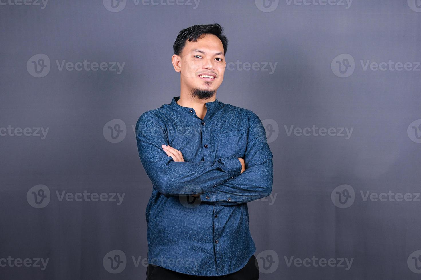 homme asiatique souriant avec chemise bleue debout avec les mains jointes isolé sur fond gris. concept d'emplois d'ingénierie photo