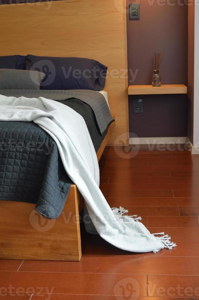 sommier, chambre avec tapis au sol, pot en argile au fond, crédence en bois et miroir. photo